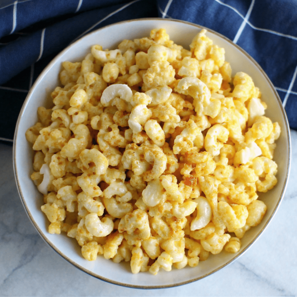 A bowl of creamy baked macaroni and cheese with a golden crust, served on a marble surface